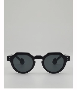 Detail of black hexagonal sunglasses featuring silver rivets and wide curved temple tips