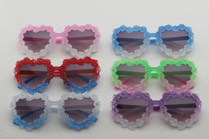 Detail view of heart-shaped kids sunglasses set with floral frame in multiple colors