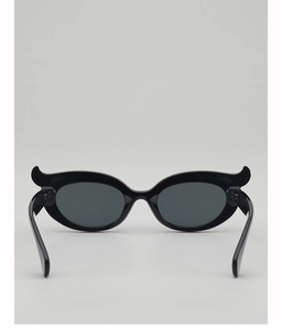 Close-up of black gothic bat-wing sunglasses with sharp pointed frame and grey lenses