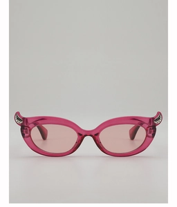 Detail of pink cat-eye sunglasses with sparkly silver wing accents on the frame corners