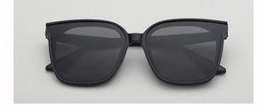 Front view of black square oversized sunglasses with dark lenses on a grey background