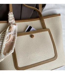 Dettaglio borsa tote in pelle crema con tasca esterna marrone e sciarpa floreale annodata