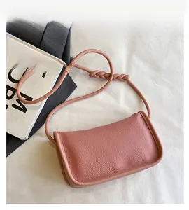 Detail of pink lychee textured leather crossbody bag with braided shoulder strap knots