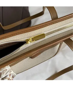 Dettaglio della cerniera dorata e cuciture della borsa tote beige con bordi a contrasto