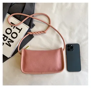 Pink litchi grain leather crossbody bag size comparison with a smartphone