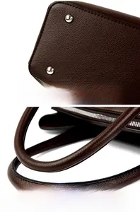 Close-up of the round handle and silver protective rivets on dark brown shoulder bag
