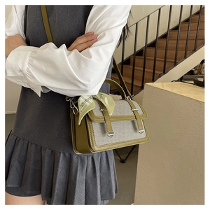 Green leather and canvas crossbody bag with decorative silk scarf on shoulder