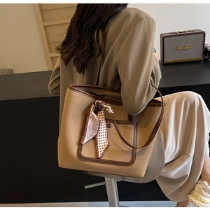 Dettaglio della borsa tote in pelle kaki con tasca marrone a contrasto e sciarpa di seta