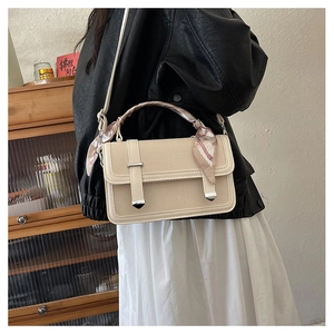 Detail of beige woven handbag with floral silk scarf handle and slim shoulder strap