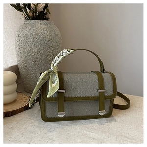 Detail of olive green woven handbag featuring a silk scarf handle and leather strap