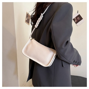 Close-up of white lychee texture leather shoulder bag with stylish knotted strap detail