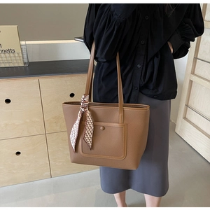 Dettaglio della borsa tote in pelle marrone con sciarpa di seta e tasca frontale a patta