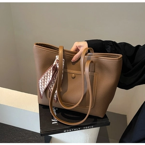Dettaglio borsa tote color caramello con trama litchi e foulard in seta stampato