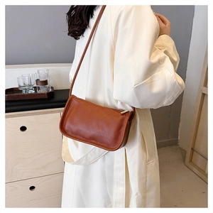Brown litchi grain faux leather underarm bag worn by a model in a minimalist setting