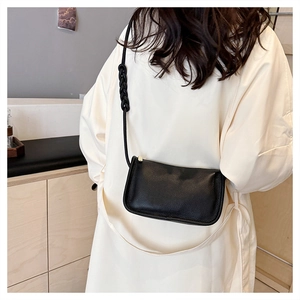 Detail of black lychee texture leather crossbody bag with woven knot strap design