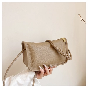 Detail of tan litchi grain leather shoulder bag featuring woven rope strap and gold zipper