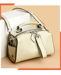 Detail of off-white faux leather pillow bag featuring geometric stitching and silver hardware