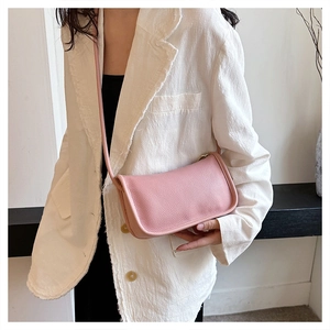 Close-up of pink litchi textured PU leather cross-body bag worn with a white blazer
