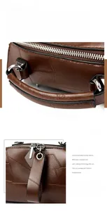 Detail of brown leather Boston bag featuring reinforced handles and dual metal zippers