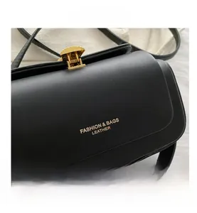 Detail of a black leather box bag featuring a gold serrated clasp and fashion branding