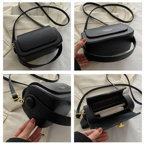 Detail view of black box bag with wide strap, golden hardware, and internal storage space