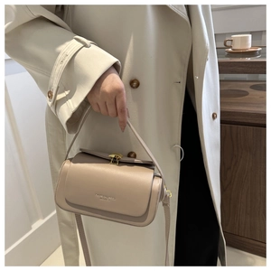 Detail of beige box bag featuring a gold twist-lock and elegant leather texture