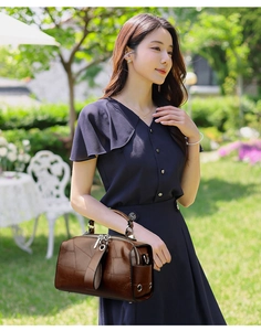 Close-up of brown Boston bag with geometric stitching and premium metal hardware details