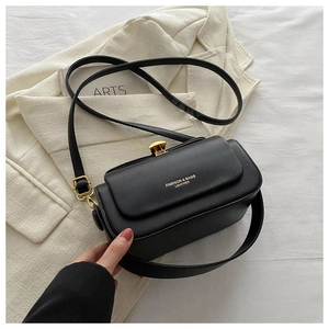 Close-up of black leather box bag with gold metal clasp and dual shoulder straps