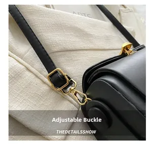 Detail of adjustable golden buckle on a black leather handbag with a shoulder strap