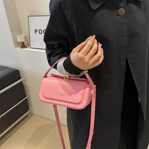 Pink leather crossbody box bag with gold lock and top handle held by a model