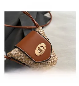 Detail of woven straw texture with brown leather flap and golden twist lock closure
