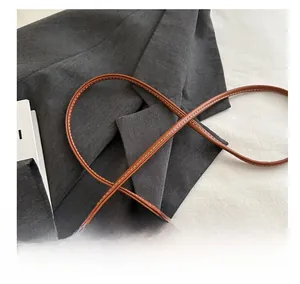 Detail of a brown leather shoulder strap featuring contrast white stitching for handbag