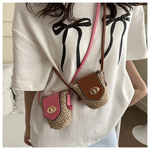 Close-up of mini woven straw crossbody bags in pink and brown with metal twist locks