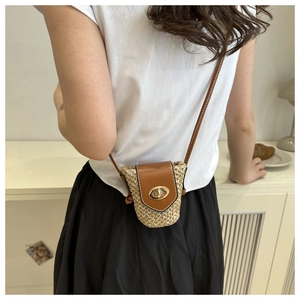 Detailed view of woven straw mini bag with brown leather flap and gold twist lock