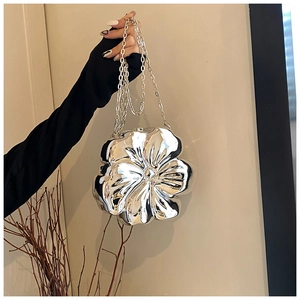 Close-up of silver flower-shaped chain bag with metallic texture and petal relief detail