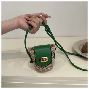 Close-up of green mini woven crossbody bag with gold metallic twist-lock being held