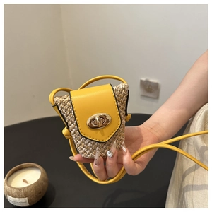 Detail of mini straw woven crossbody bag with yellow leather flap and golden lock