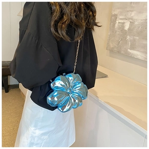 Crossbody shot of a metallic blue flower-shaped bag with a gold chain strap