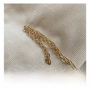Detailed close-up of premium golden metal chain strap on a soft knit fabric background