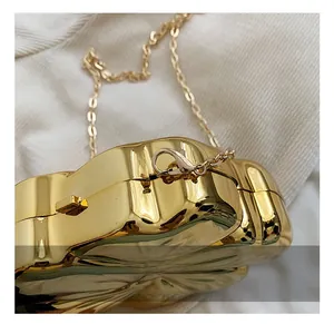 Close-up of gold flower-shaped clutch with detachable metallic chain and lobster clasp