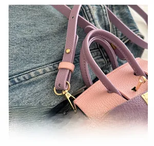 Gros plan sur le sac en cuir rose et violet avec boucle dorée et bandoulière ajustable