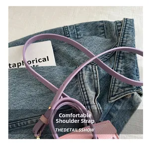 Détail de la bandoulière en cuir à grain litchi avec boucle dorée sur sac violet