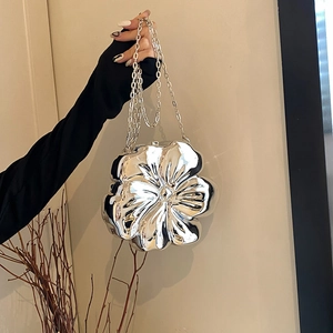 Silver flower petal shaped metal chain clutch bag shown from a hand-held front perspective