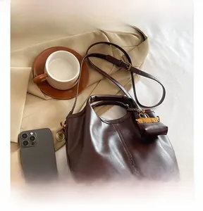Detail view of brown PU leather crossbody bag with adjustable strap and small coin purse charm