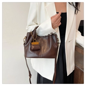 Detail of dark brown vintage faux leather shoulder bag with a matching mini pouch charm