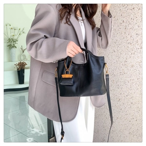 Detail of black leather handbag with gold chain mini charm and detachable shoulder strap