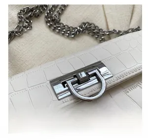 Detail shot of the silver metal rotating lock on a white crocodile-patterned bag