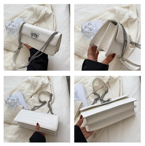 Detail of white crocodile embossed shoulder bag with chain strap and accordion structure