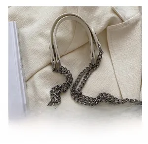 Close-up of a white crocodile texture bag with metal chain and leather strap detail