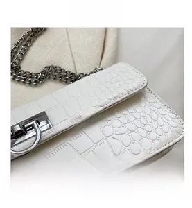 Detail of white crocodile pattern shoulder bag with silver metal chain and clasp
